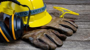 Hardhat with work gloves, headphones, and safety glasses