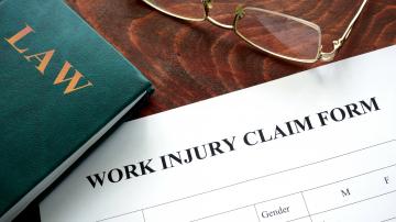 Work Injury claim form, law book, and pair of glasses